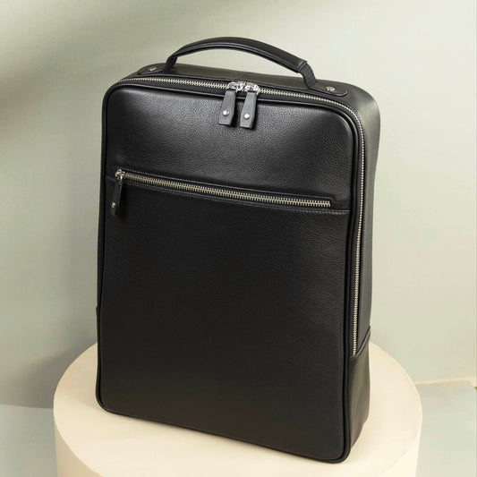 A black leather backpack with a top handle, zippered closure