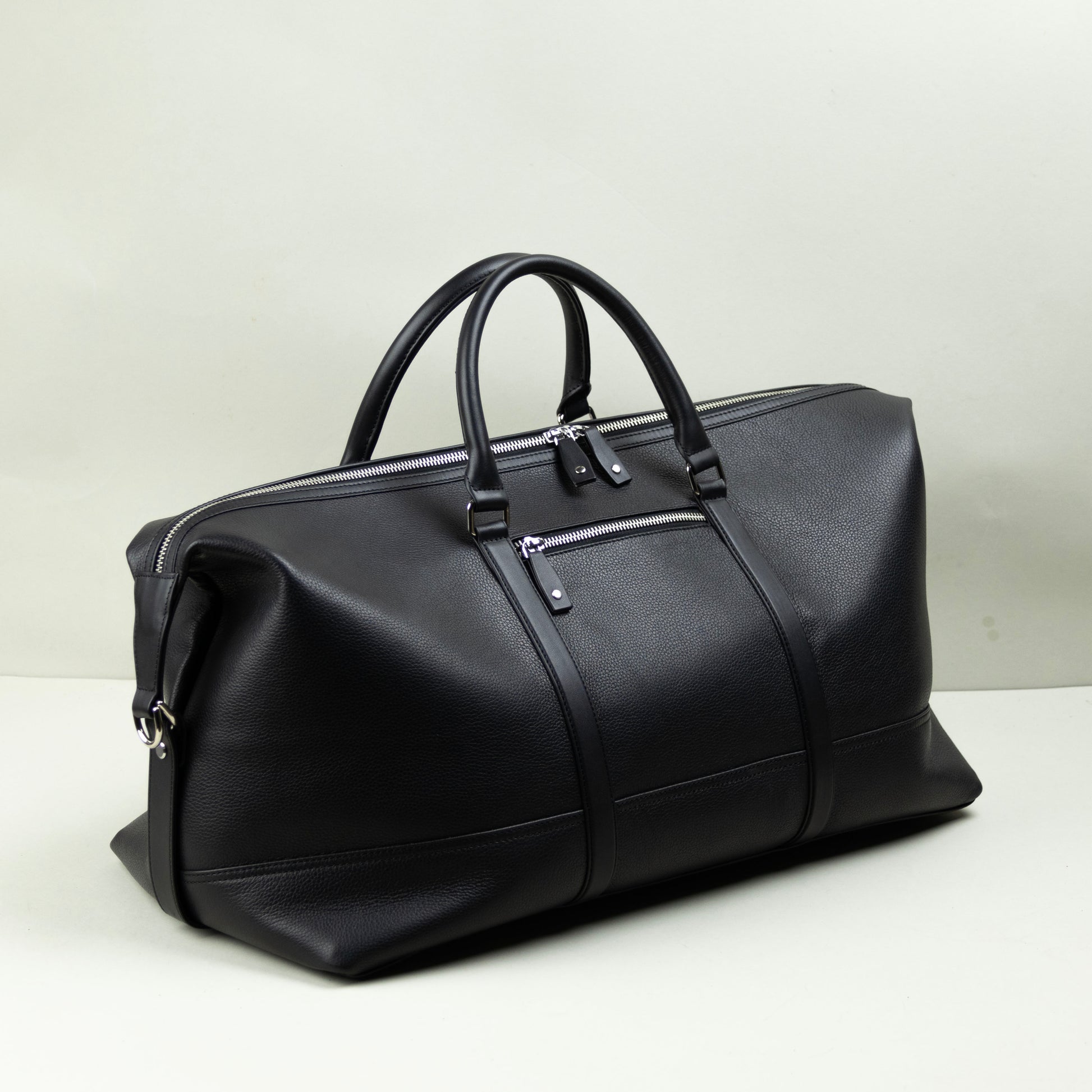 Black leather duffel bag on a light gray background