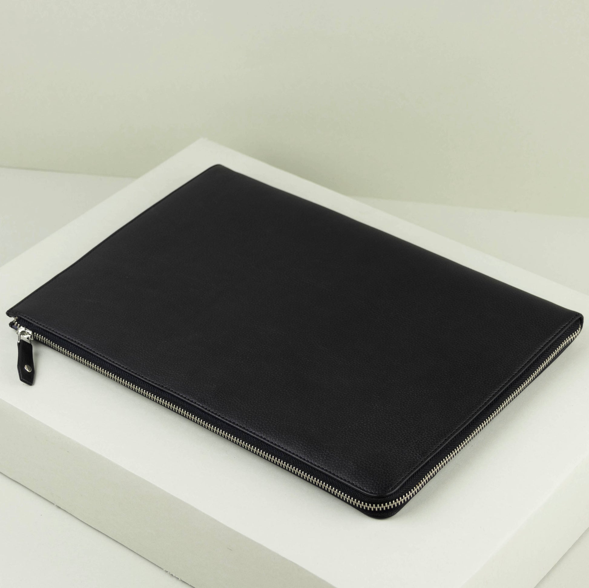 Black zippered laptop pouch on a white surface