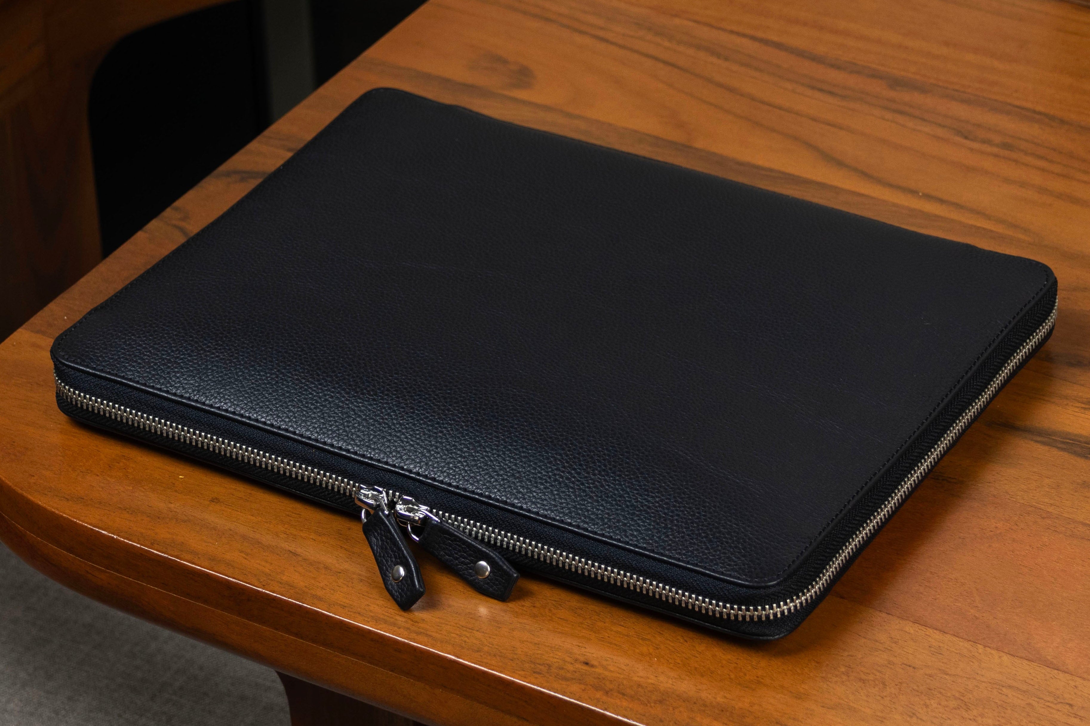Black leather zippered case on a wooden table