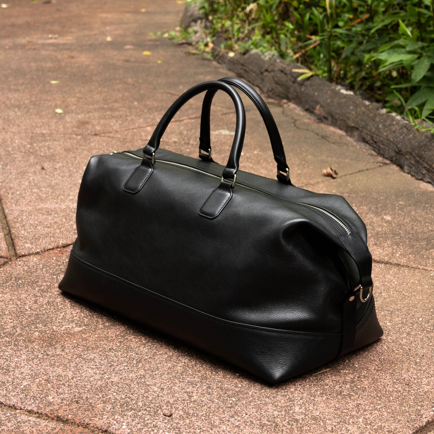 Leather Duffle Bag in Black. Designed with top handles and a zipper closure
