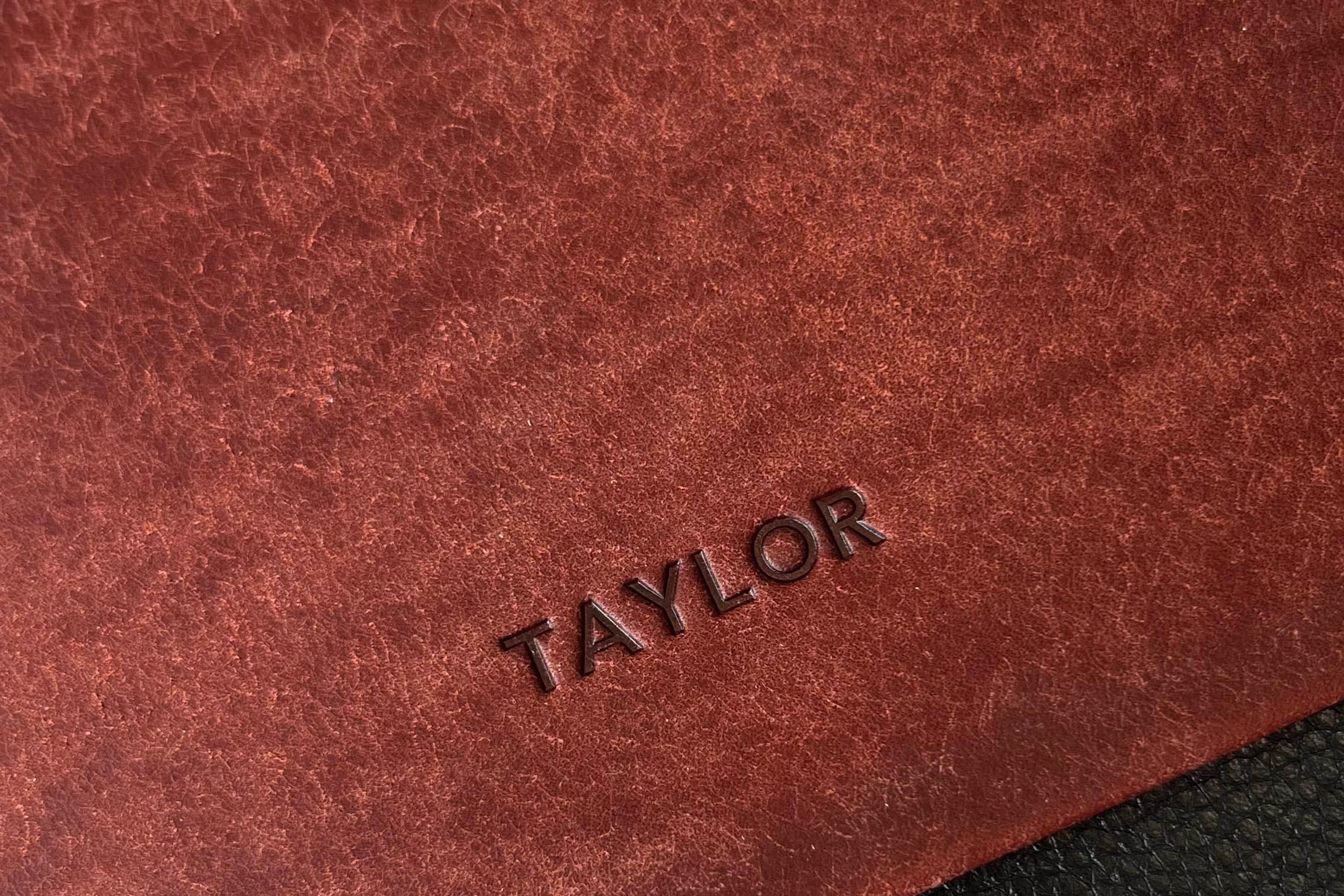Close-up of brown leather surface with 'TAYLOR' branding, next to black leather surface.